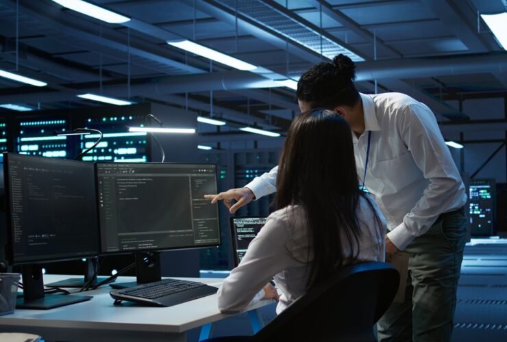 Dua teknisi IT sedang memantau sistem jaringan dan keamanan server infrastruktur IT bisnis di ruang data center