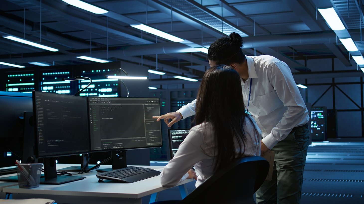 Dua teknisi IT sedang memantau sistem jaringan dan keamanan server infrastruktur IT bisnis di ruang data center